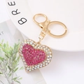 Makroaufnahme eines rosa Herz-Schlüsselanhängers mit Strass und goldenem Karabinerverschluss - Zweifarbiges Strass Rosa Herz