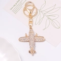 Detailaufnahme eines glitzernden Gold-Flugzeug-Schlüsselanhängers mit Strass auf einer Karte - WeiBer Strass (Farbe 3)
