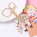 Detailed macro view of white enamel elephant keychain with sparkling rhinestones and gold flowers - White