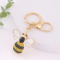 Détail d'un porte-clés abeille avec des strass jaunes et noirs et un anneau doré - Ailes Blanches (Couleur 6)