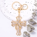 Dettaglio di un portachiavi a croce dorata con strass bianchi e ciondolo a nastro decorativo - Oro (Strass Bianco)