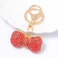 Dettaglio ravvicinato del ciondolo a fiocco con strass rossi e anello portachiavi dorato - Rosso