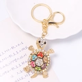 Squisito portachiavi a tartaruga in metallo dorato con strass colorati su sfondo bianco - Colorato