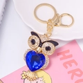 Dettaglio ravvicinato del portachiavi a gufo dorato con cristallo a cuore blu e strass - Blu