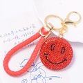 Close-up of red rhinestone smiley face keychain with woven lanyard and golden lobster clasp - Red Smiley Face With Leather Strap