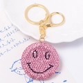 Dettaglio del portachiavi a forma di faccina con strass rosa e chiusura dorata su piatto bianco - Ciondolo Smiley Rosa