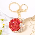 Close-up of snail keychain featuring red enamel shell and sparkling crystal rhinestones - Red