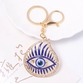 Detaillierte Makroaufnahme eines goldenen Evil Eye Schlüsselanhängers mit blauer Emaille - Rotes Auge Stil