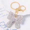Detail of golden bow keychain with sparkling rhinestones and lobster clasp on white tray - Clear Rhinestone Bowknot Pendant (Color 4)