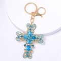 Dettaglio del portachiavi a croce dorata con strass blu scintillanti e chiusura a moschettone - Cuore e Croce / Blu