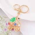 Dettaglio macro del portachiavi a carrozza cigno dorata con gemme e strass colorati - Verde