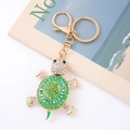 Dettaglio di un portachiavi a forma di tartaruga con strass in cristallo verde e blu lucido - Verde