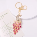 Detail view of crystal peacock keychain with sparkling rhinestones and golden metal ring - 8.8cm x 4.1cm / Pink