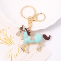 Détail d'un porte-clés cheval plaqué or avec émail bleu et strass blancs scintillants - Bleu lac