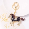 Macro shot of horse keychain with crystals on a golden base and lobster clasp detail - Black