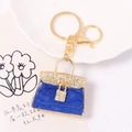 Portachiavi borsa in smalto blu con strass e anello dorato su un vassoio decorativo - Stile Borsa in Smalto Blu Profondo