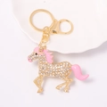 Detail shot of a golden horse keychain with white rhinestones and pink enamel finish - Pink