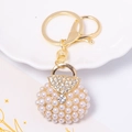 Dettaglio portachiavi a forma di borsa con perle incastonate, anello dorato e strass lucidi - Stile Perla Bianco Crema (Colore 2)