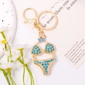 Close-up of golden bikini keychain with blue rhinestones and cute bow on a card - Aqua