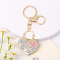 Dettaglio portachiavi a cuore con strass e fiori in smalto su base in metallo dorato - Fiore Blu