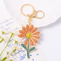 Detailed macro view of sparkling rhinestone sunflower keychain in a bright setting - Orange Red