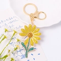 Close-up of a sparkling metal daisy keychain with colorful yellow and blue rhinestones - Yellow