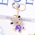 Vista macro di un portachiavi a forma di bue dorato con strass e smalto viola - Viola