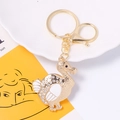 Close-up of golden dodo keychain with rhinestones and enamel details on decorative tray - White