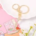 Close-up of gold metal letter L keychain with white rhinestones and a red heart charm - Letter I