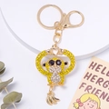 Détail du porte-clés singe doré orné de cristaux jaunes et d'un petit pendentif banane - Jaune