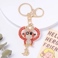Détail du porte-clés singe en cristal avec strass rouges et breloques bananes dorées - Rouge