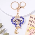 Porte-clés gorille en strass bleu avec pendentif banane dorée sur fond blanc - Bleu