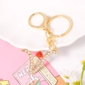 Detailed macro of gold metal V letter keychain with sparkling crystals and a red heart stone - Letter V