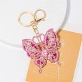 Detailed macro view of pink butterfly keychain with crystals on a decorative floral card - Pink