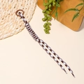 Detailed view of brown houndstooth braided phone strap with a round plastic clip - Brown Houndstooth