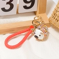 Detail von rotem Leder-Flechtband und goldenem Schlüsselanhänger mit buntem Strass-Schwein - Weißes Schwein Mit Geflochtener Schnur