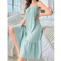 Detail of mint green slip dress showing vertical stripe texture and ruffle hem on the bed - Light Green