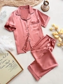 Détail d'un pyjama en satin rose avec liseré noir contrasté et design boutonné classique - S / Corail