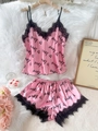 Detalle de pijama de seda rosa con estampado love y ribete de encaje negro sobre piel - S / Rosa