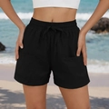 Detalle de shorts playeros negros con cordón, cintura elástica y bolsillos en fondo de playa - S / Negro