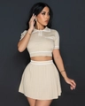 Detail of knitted pleated two-piece set featuring cream polo shirt and mini skirt - Apricot