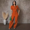 Close-up of rust orange jumpsuit featuring puff short sleeves and button chest pockets - Orange