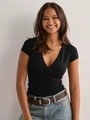 Detail of a slim fit black V-neck wrap short sleeve T-shirt styled with denim jeans - S / Black