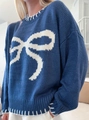 Close-up of blue knit sweater featuring a white bow pattern and contrast stitching - S / Blue