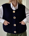 Detail van donkerblauw gebreid vest met gouden knopen over een wit shirt - S / Marineblauw