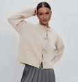 Detail of cream knit cardigan featuring elegant front bow tie closures and ribbed texture - Apricot
