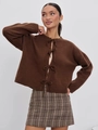 Detail of dark brown knitted cardigan featuring decorative bow closures and ribbed cuffs - Coffee