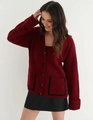 Detail eines weinroten V-Ausschnitt-Cardigans mit grobem Strick und schwarzen Taschen - S / Rot