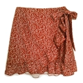 Detail of red floral wrap skirt with tie-waist bow and elegant ruffled hem design - S / Red