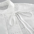 Primer plano detallado del bordado floral y el encaje calado en una blusa blanca de algodón - S / Blanco